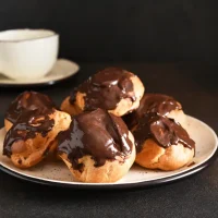 Profiteroles,With,Vanilla,Cream,And,Chocolate,Sauce,With,A,Cup