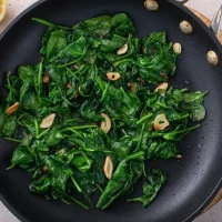 Sauteed,Garlic,Spinach,In,A,Cooking,Pan,With,Slices,Of